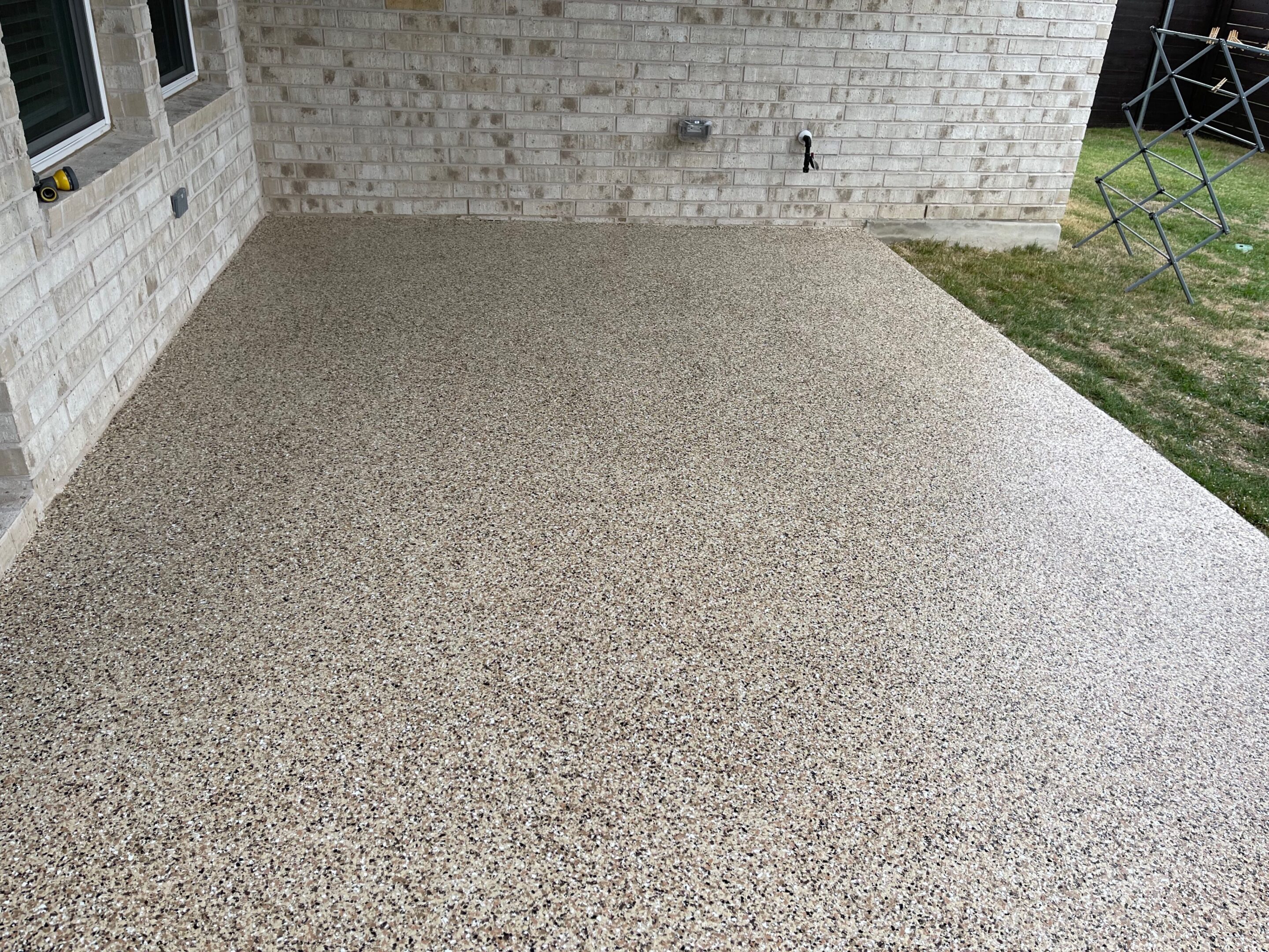 A patio with a brick wall and concrete floor.